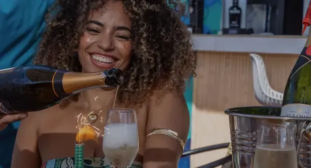 Una invitada sonríe mientras le sirven champaña en una celebración del rooftop.
